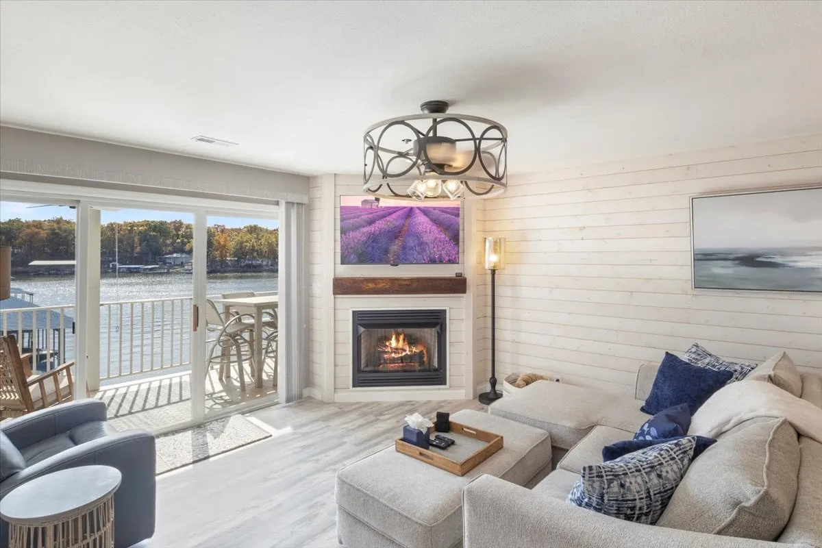 A warm and welcoming living area featuring a gas fireplace, comfortable seating, and large windows that offer breathtaking views of the lakefront. The scene suggests relaxation, intimate conversations, and the enjoyment of scenic sunsets from the comfort of the interior.