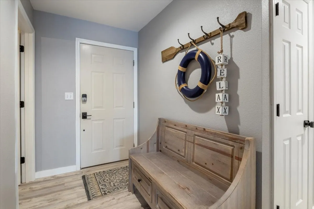 A calm, welcoming entryway with a decorative bench, life preserver, and a cheerful welcome sign. The atmosphere evokes first impressions and a sense of hospitality, suggesting the beginning of a memorable getaway or exploration of the surrounding area.