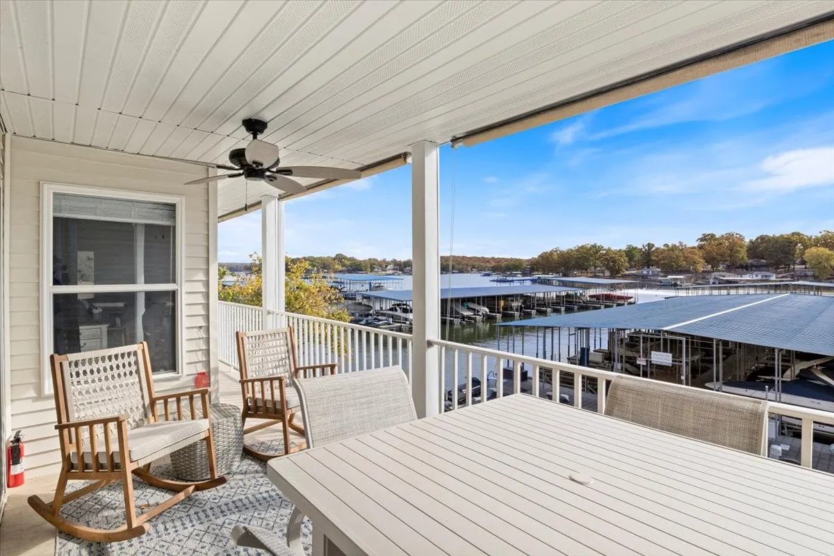 An inviting outdoor area with rocking chairs and a dining table overlooks the marina. The water and boats are visible in the background, offering a tranquil yet active setting suited for lakeside relaxation after a day on the water.