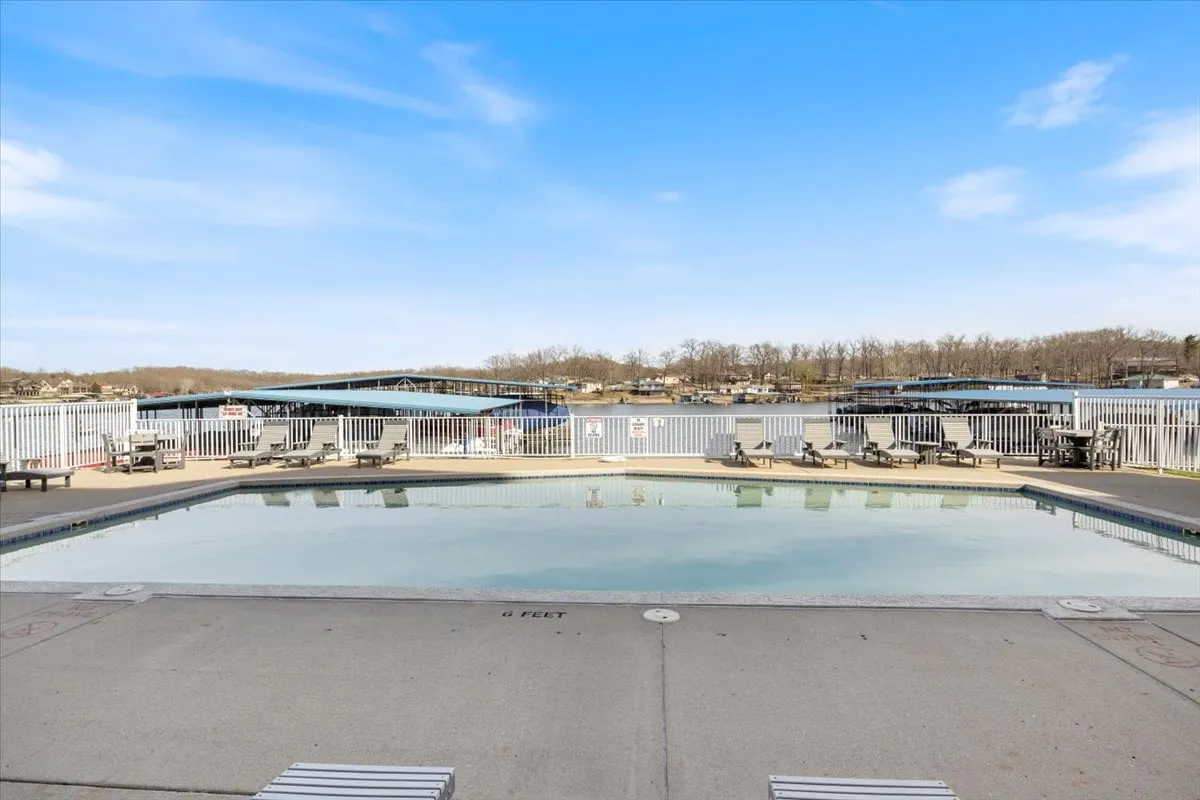 An exterior shot featuring a sparkling swimming pool with lounge chairs arranged around the perimeter. Beyond the pool, the lake is clearly visible, enhancing the sense of resort-style amenities and direct access to the water.